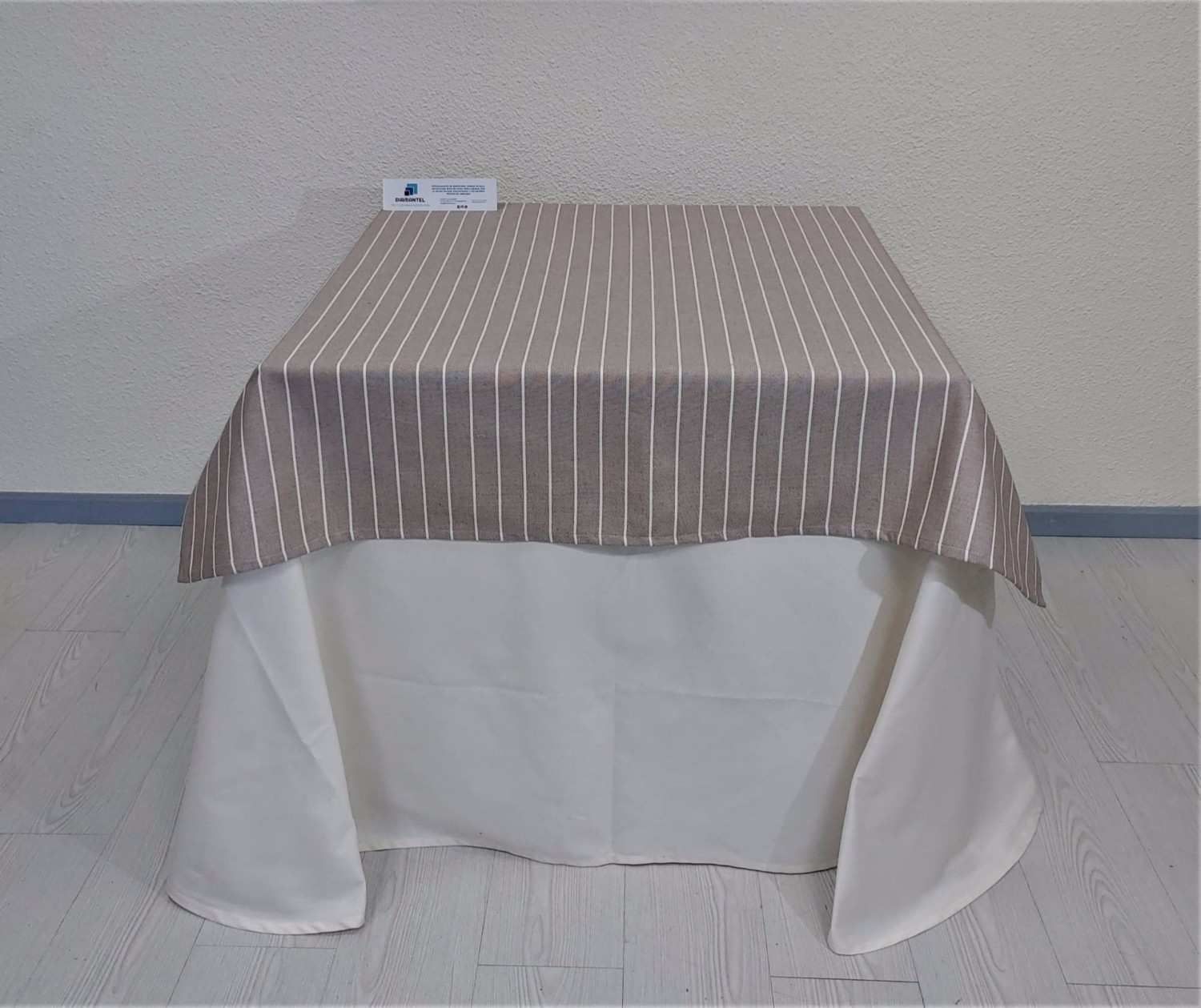 Una mesa cuadrada cubierta con un mantel de rayas beige.