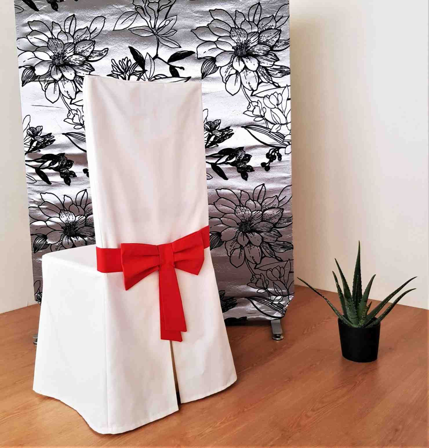 Una funda blanca para silla con un lazo rojo vibrante