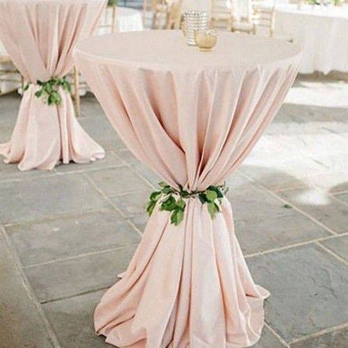 Dos mesas altas y redondas de cóctel, cubiertas con manteles de color rosa