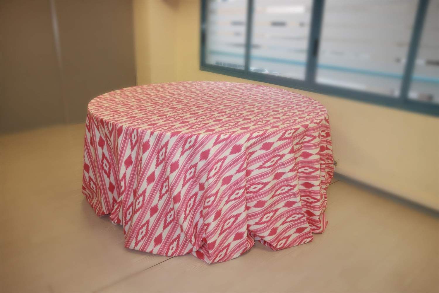 Una mesa redonda cubierta con un mantel estampado en rojo y blanco