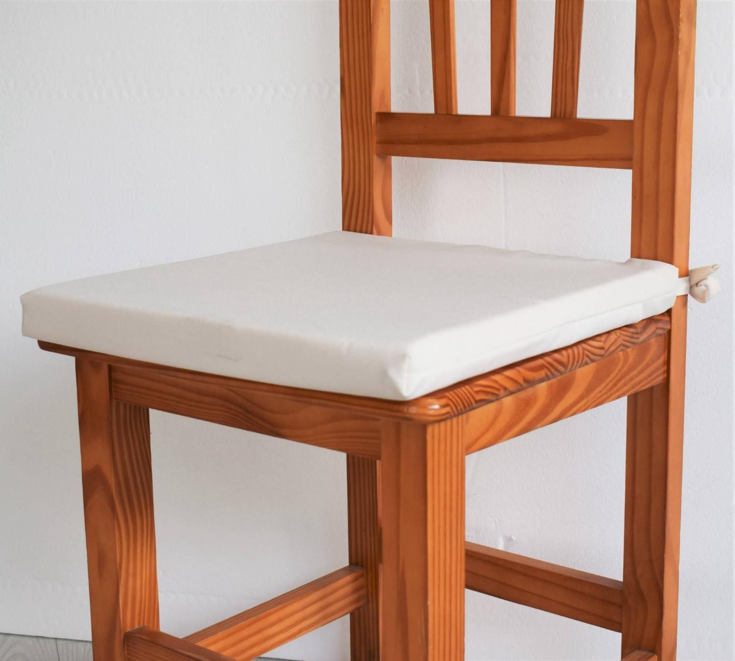Una silla de cocina de madera con un cojín de asiento liso de color beige claro.