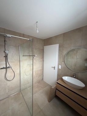 Une cuisine moderne et minimaliste avec des armoires gris foncé et un îlot assorti, située dans une pièce au parquet clair.