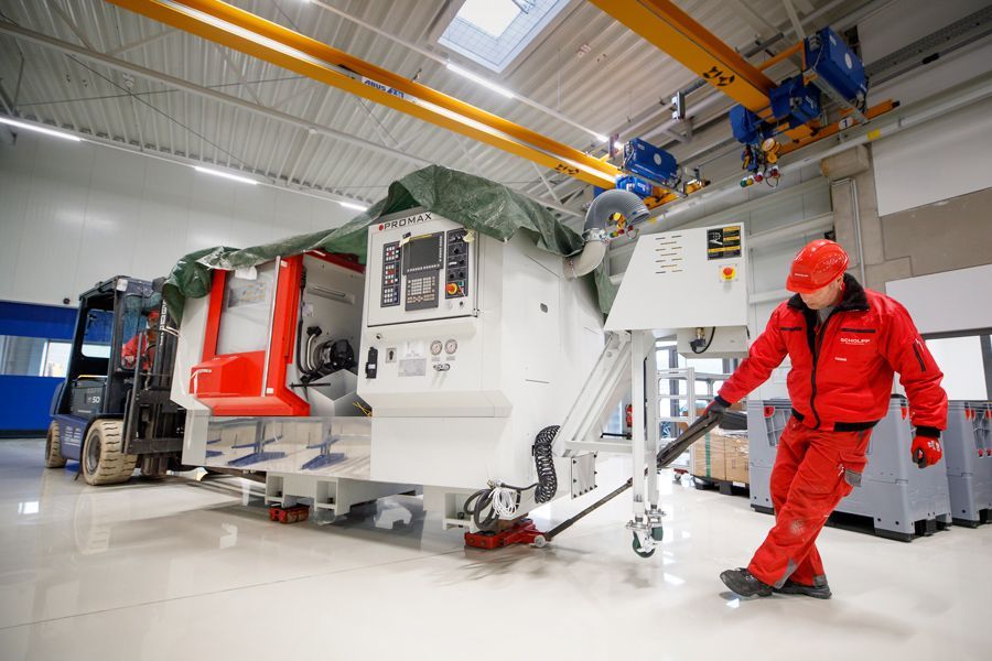 Ein Mann in einer roten Jacke schiebt eine Maschine in einer Fabrik