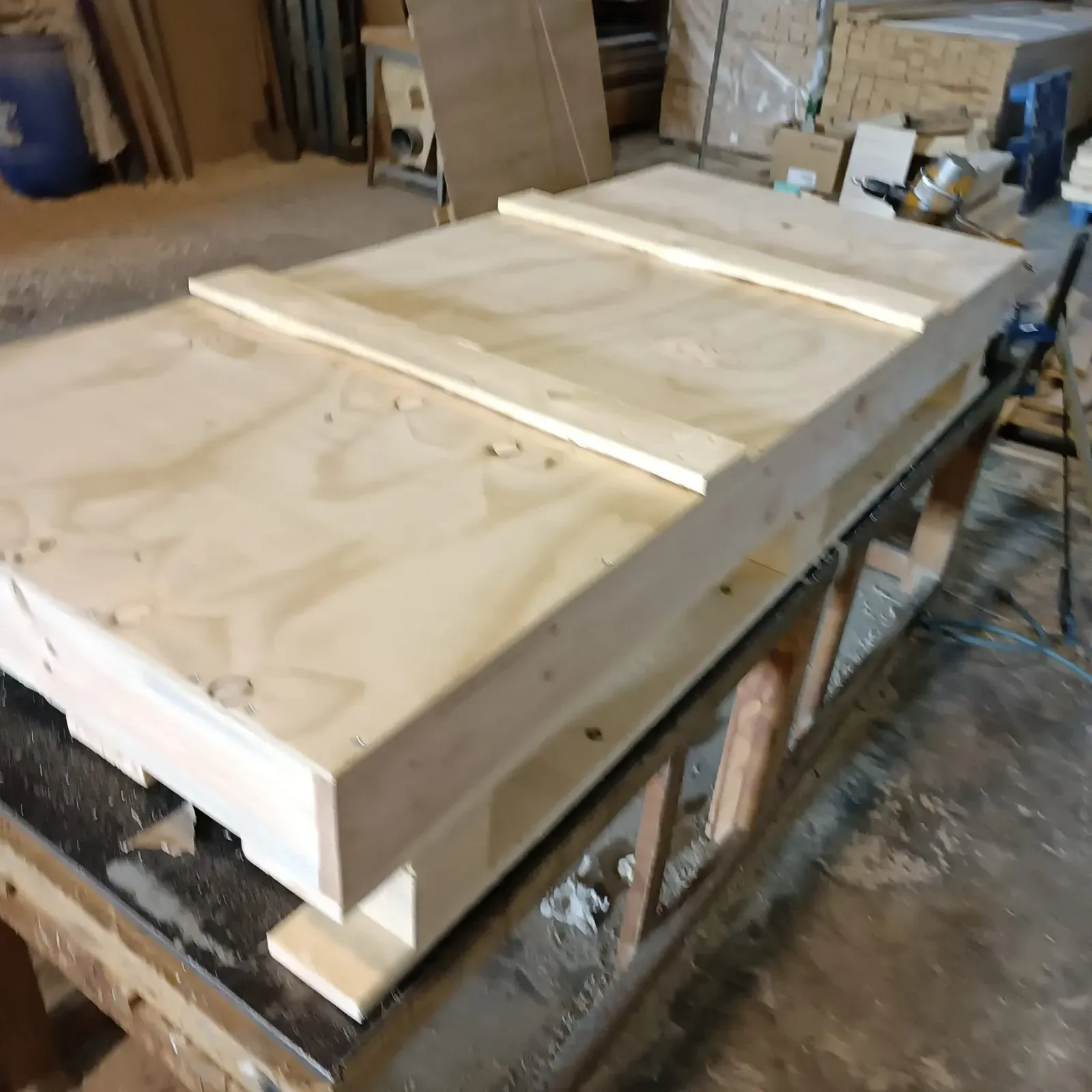 Caja de madera sobre un banco de trabajo. Tapa de contrachapado con dos soportes de madera.