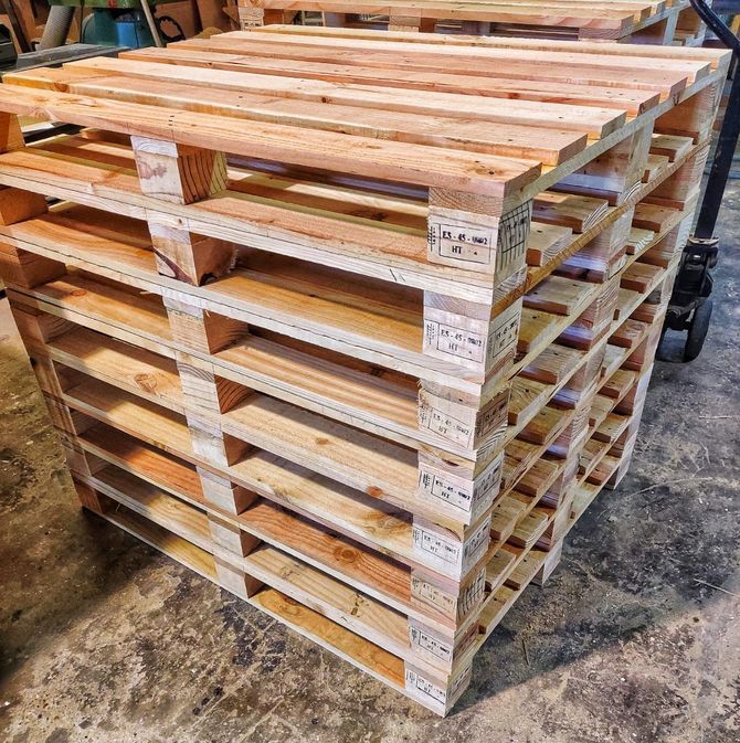 Una caja de madera sobre la plataforma de un camión, asegurada con una correa, en un entorno al aire libre.