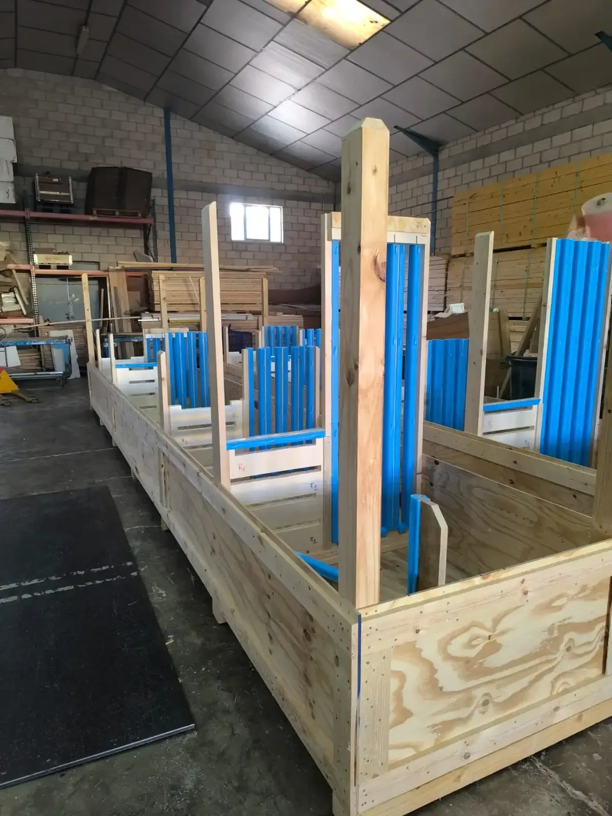 Camión cargado con pallets de madera y cartón, estacionado cerca de un edificio.