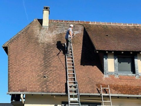 Nettoyage d'une toiture grise avec une brosse