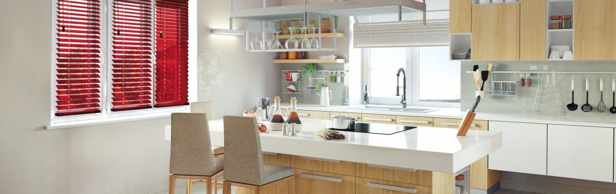 Une cuisine moderne avec un îlot blanc, des placards en bois et des stores rouges aux fenêtres.