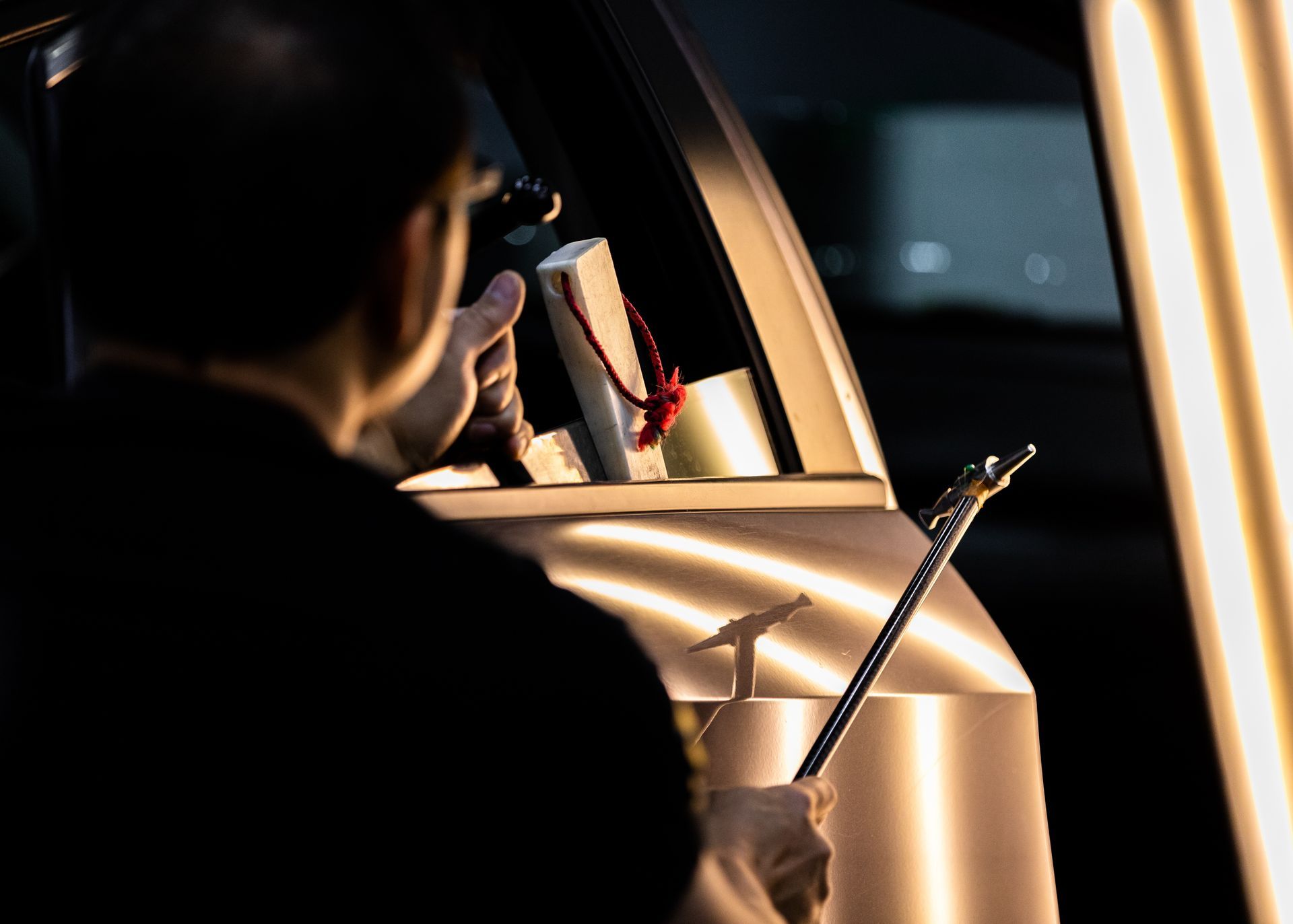 Carrossier réparant une carrosserie avec son marteau