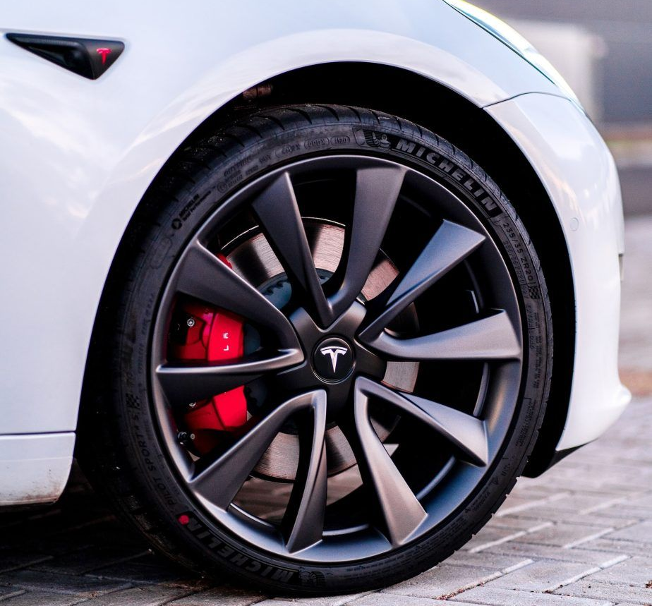 Roue de voiture Tesla blanche avec jante gris foncé et étrier de frein rouge.