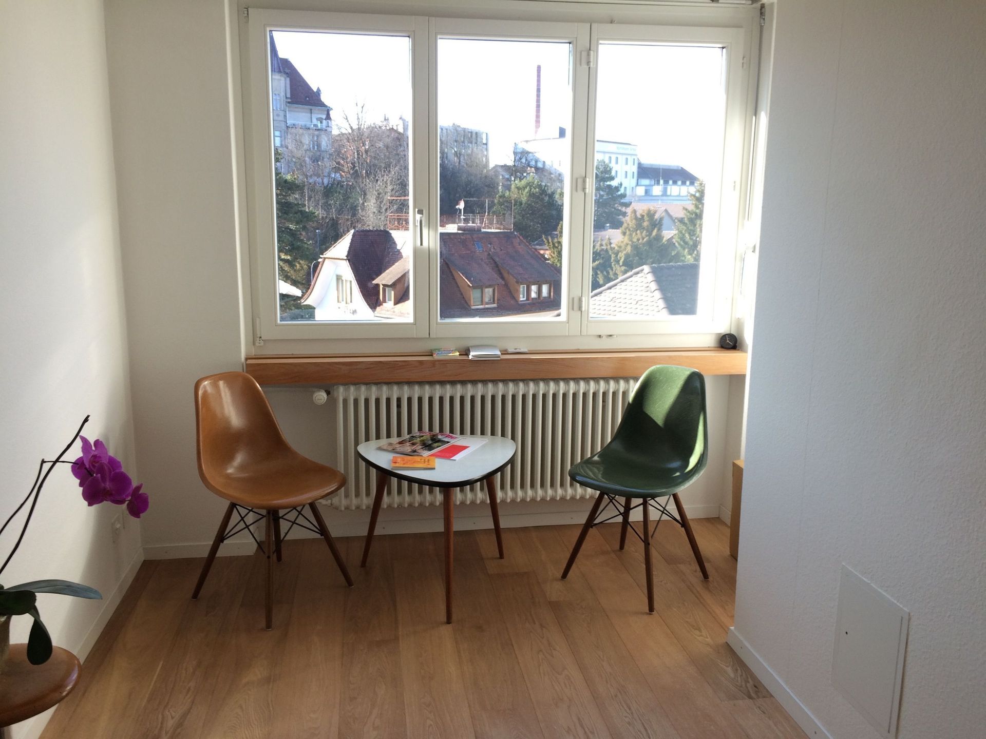 Ein Raum mit zwei Stühlen und einem Tisch vor einem Fenster.