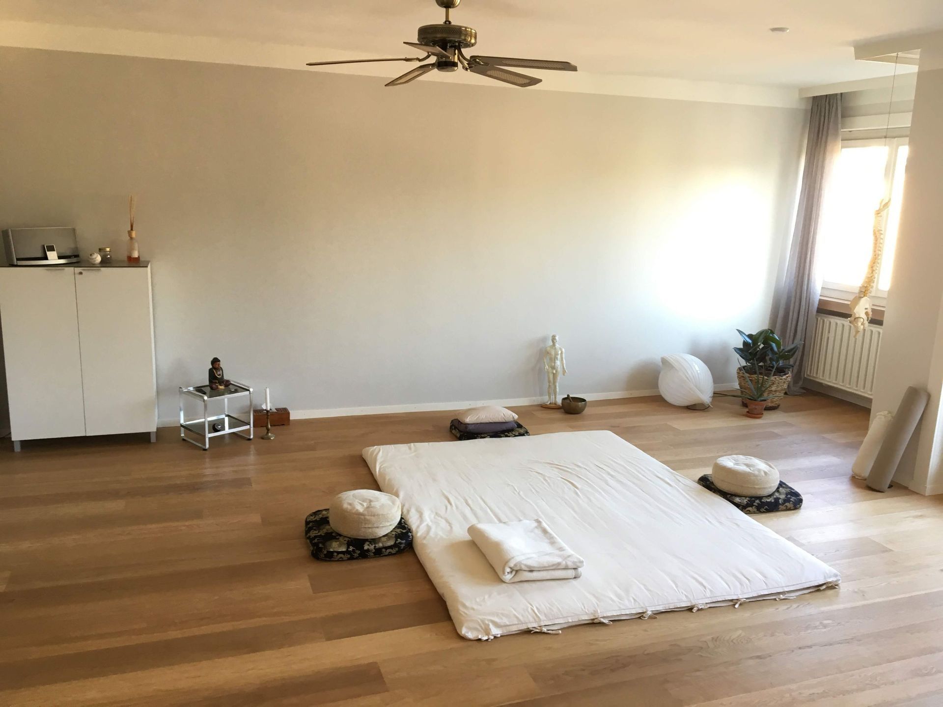 Ein Zimmer mit einem Deckenventilator und einer Matratze auf dem Boden