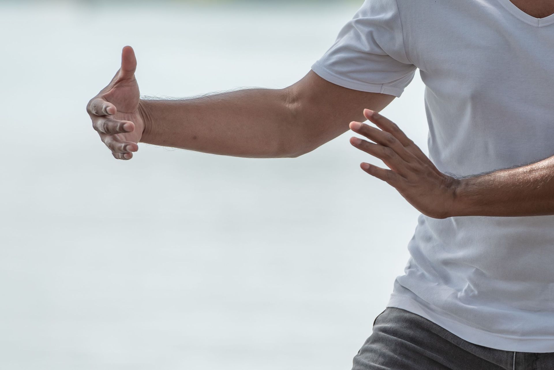 Ein Mann im weißen Hemd praktiziert Tai Chi am Strand.