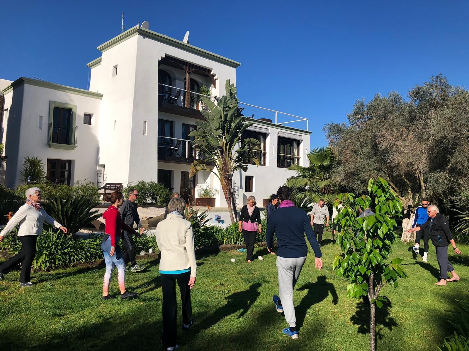 Eine Gruppe von Menschen macht Übungen im Gras vor einem Gebäude.