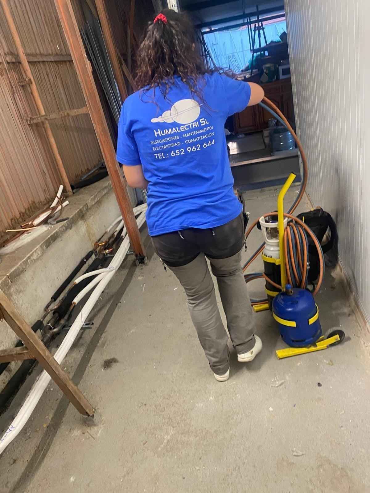 Pequeño rincón de dormitorio con aire acondicionado de pared, borde de cama y alfombra estampada.