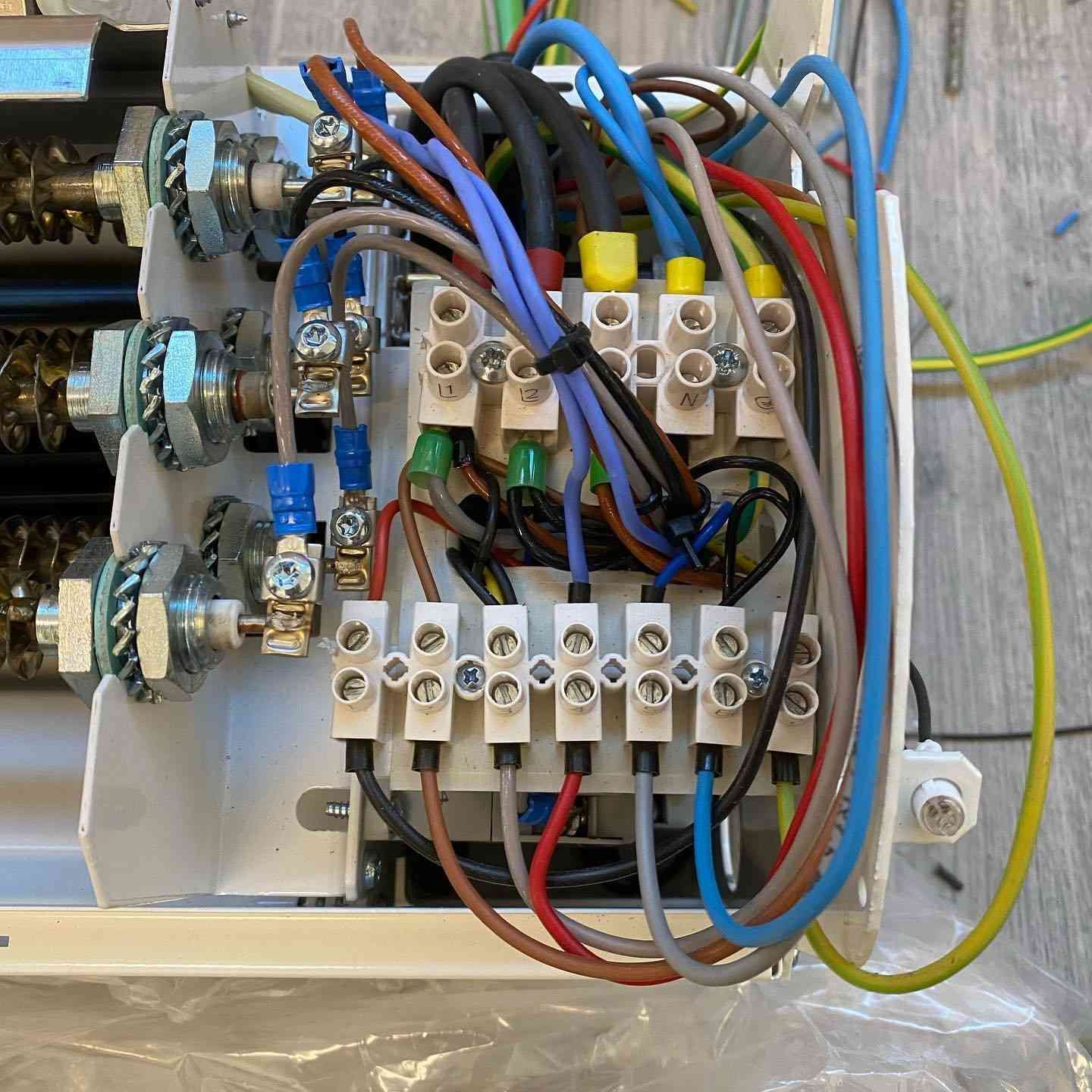 Panel de control eléctrico con cables, interruptores y bloques de terminales dentro de una carcasa metálica.
