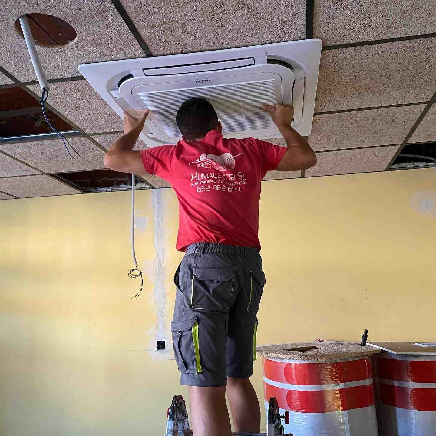 Técnico instalando un aire acondicionado de cassette de techo