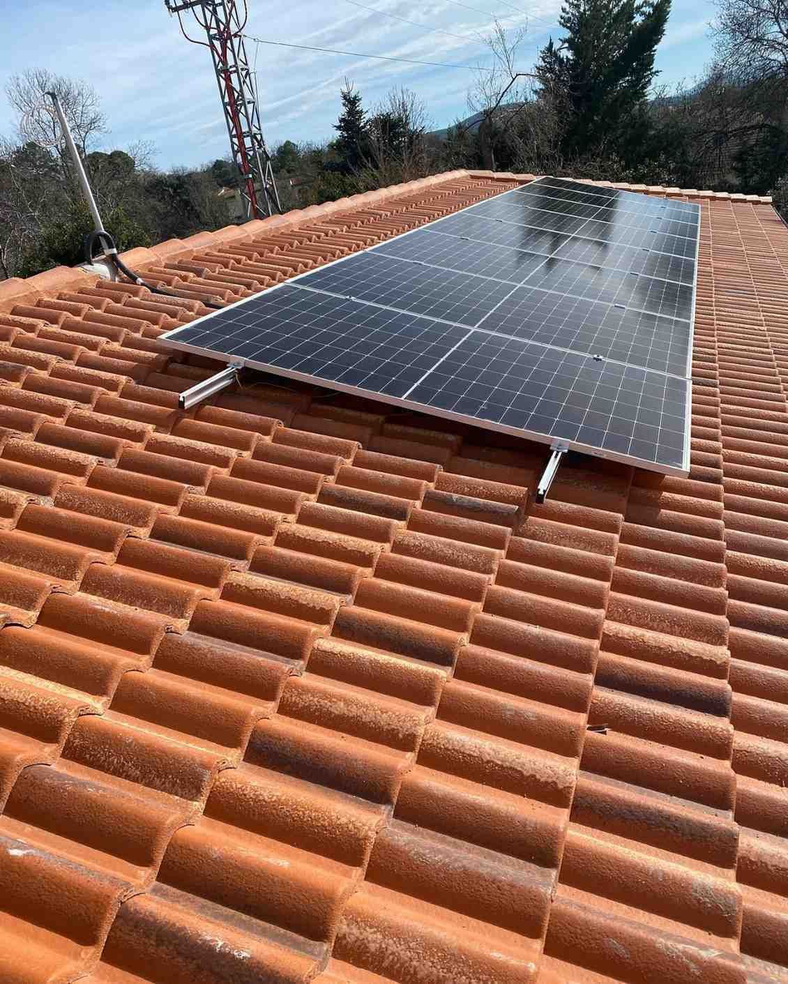 Paneles solares instalados en un tejado de tejas rojas bajo un cielo despejado.