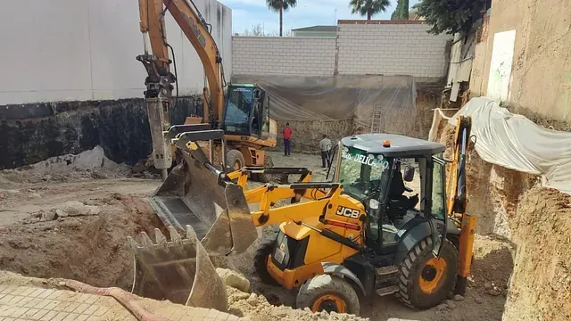 Un hombre conduce una excavadora en un sitio de construcción.