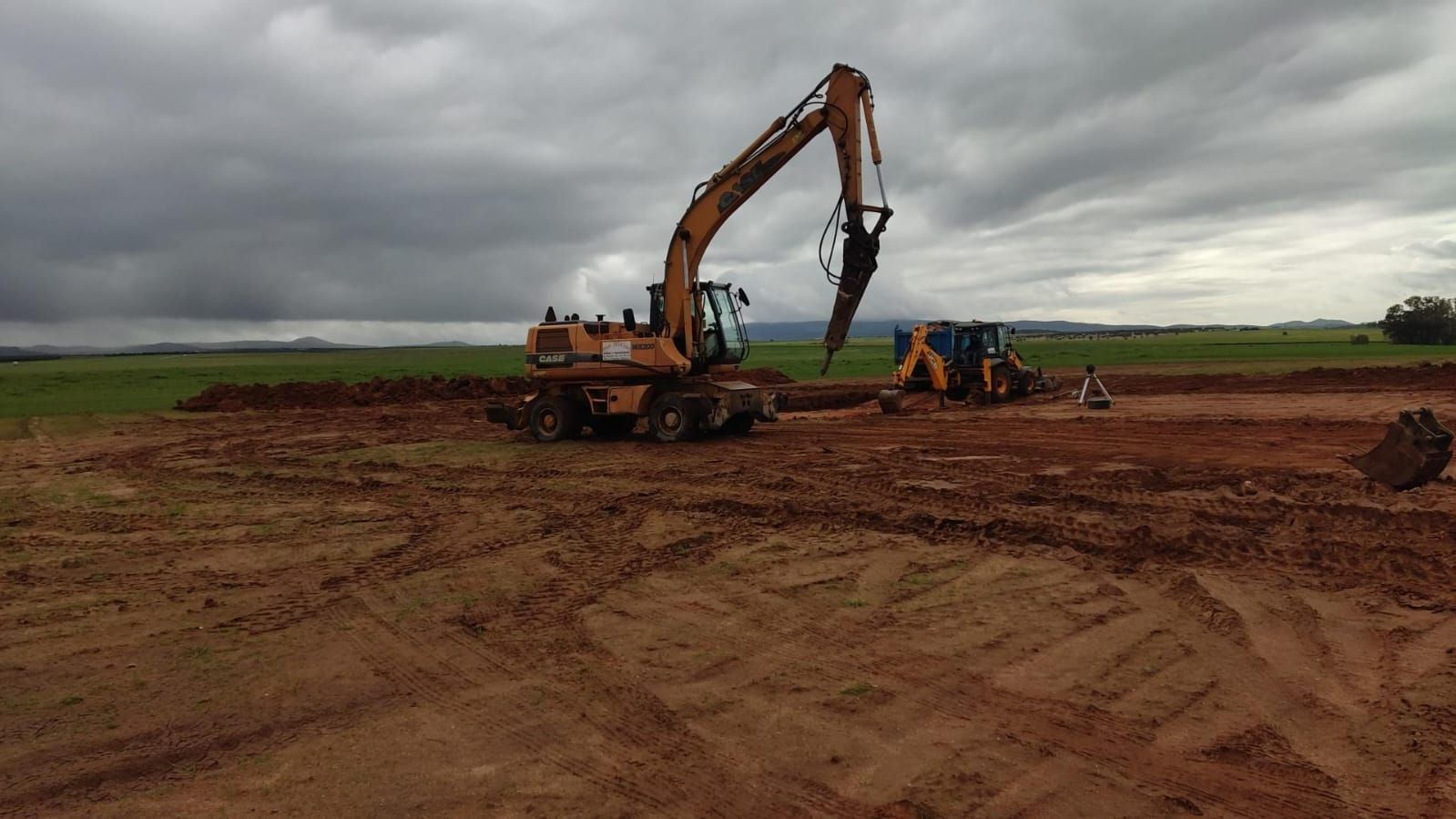 Una excavadora grande está cavando un hoyo en un campo de tierra.