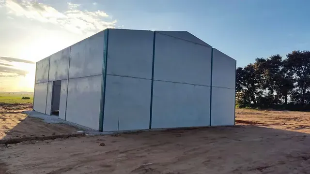 Un gran edificio blanco está situado en el medio de un campo de tierra.