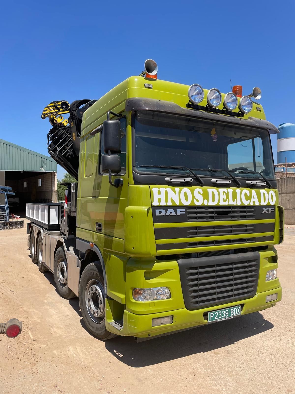 Un camión DAF verde está estacionado en un terreno de tierra.