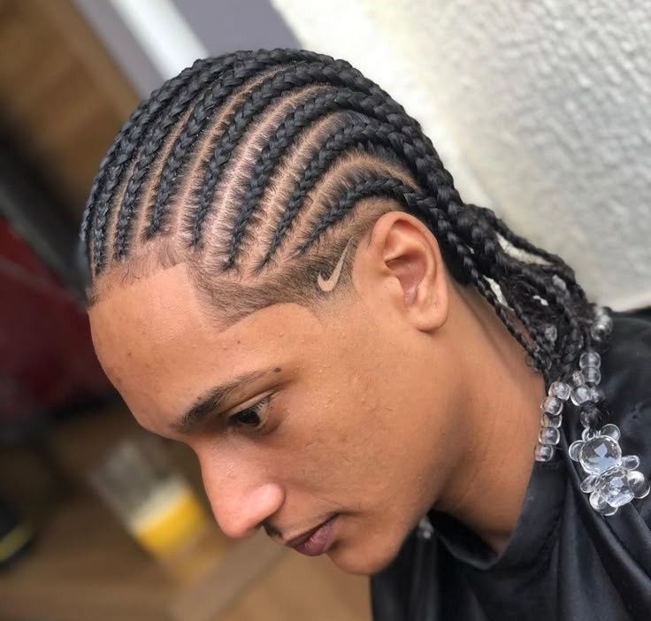 Primer plano de una persona con trenzas africanas, mirando hacia abajo en el interior de un edificio.