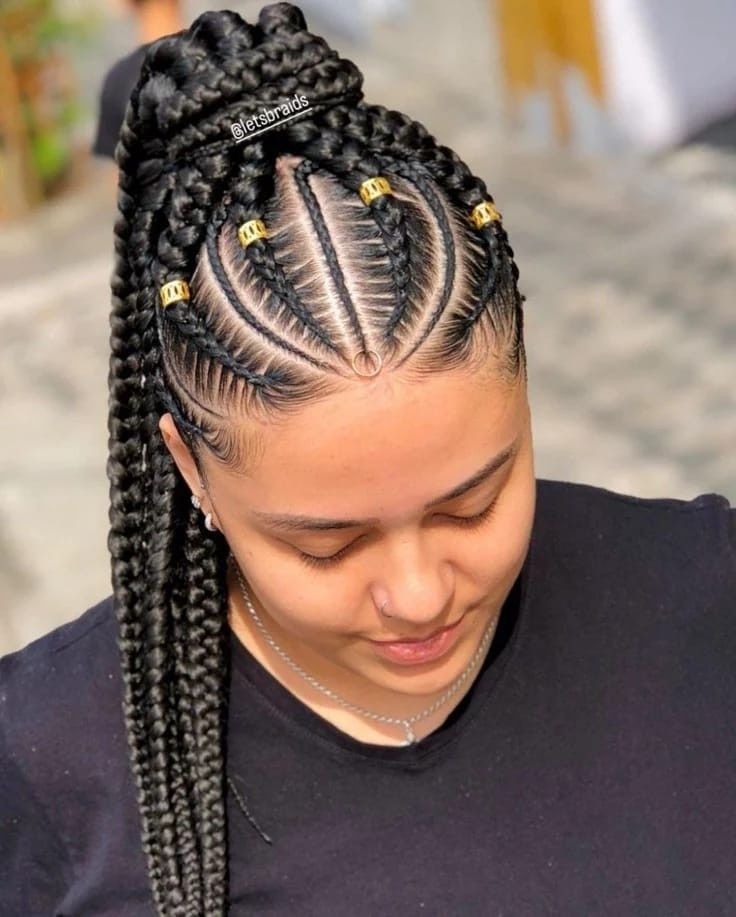 Peinado trenzado con trenzas africanas y detalles dorados, visto desde arriba sobre una blusa negra.