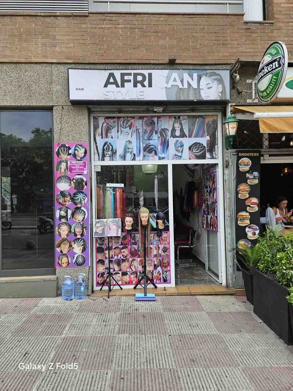 Fachada de una tienda de ropa africana con coloridos vestidos y maniquíes expuestos en el exterior.