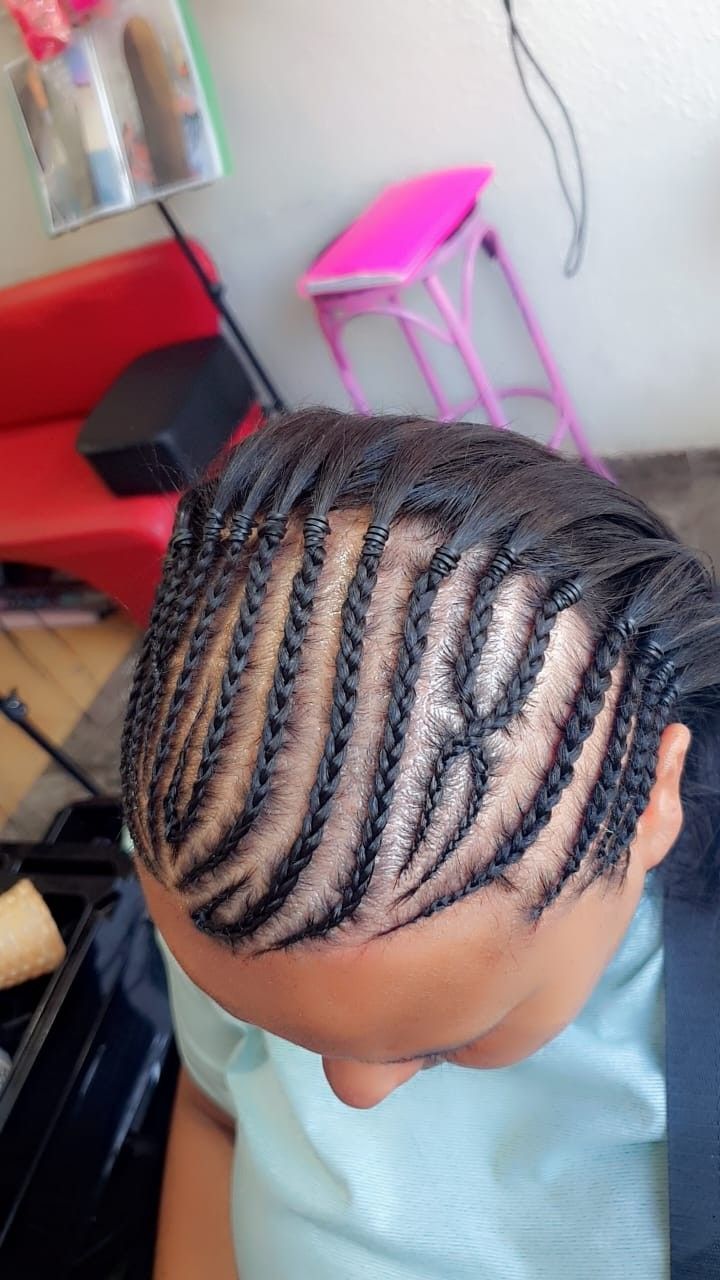 Primer plano de unas trenzas africanas bien hechas en la cabeza de una persona sentada en una silla de peluquería.