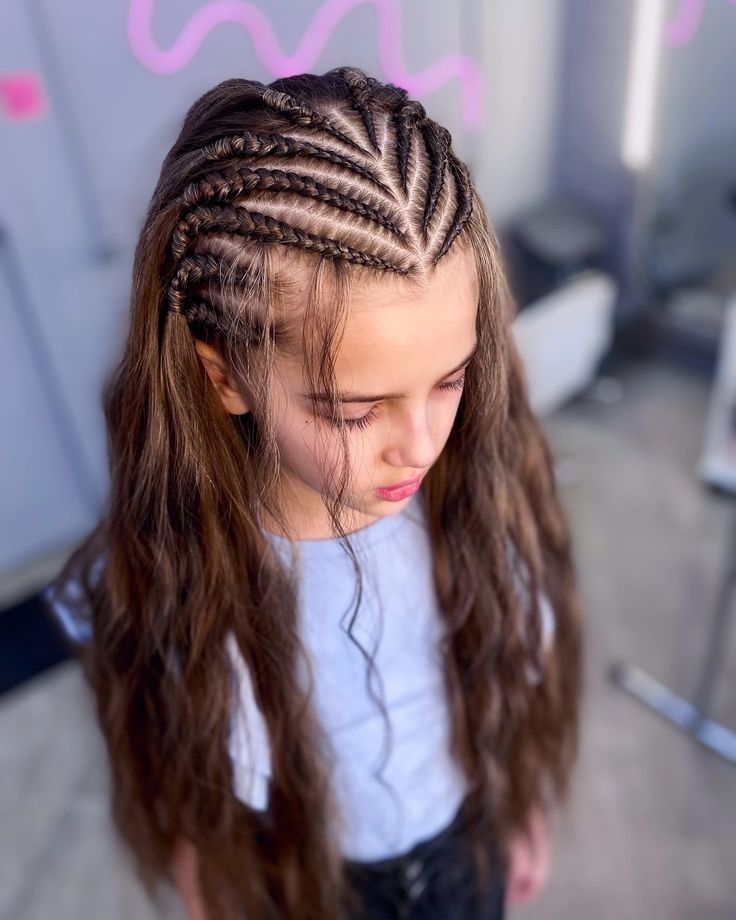 Chica con trenzas africanas y cabello largo, vestida con una camisa blanca, mirando hacia abajo al aire libre.