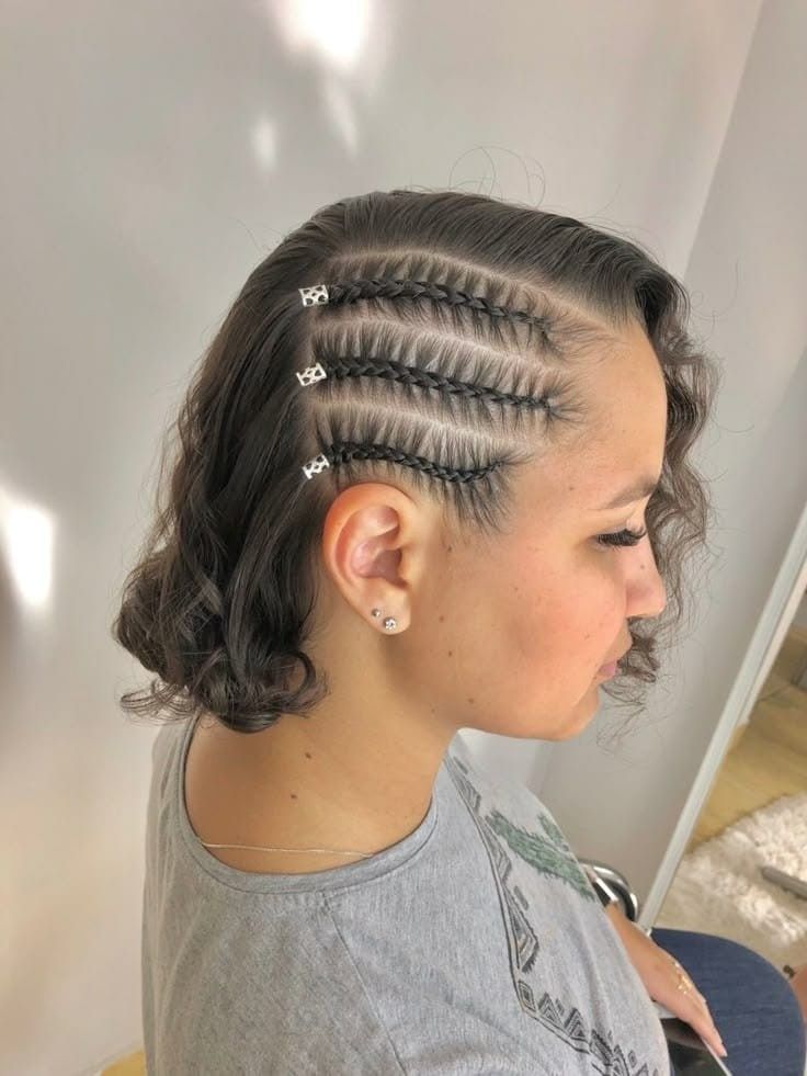 Vista lateral de una persona con trenzas africanas y horquillas para el cabello, que lleva una camisa gris en el interior