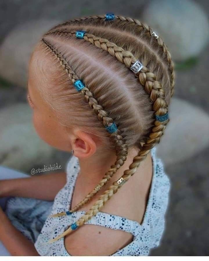 Primer plano de una trenza con cuentas azules y una pinza plateada en la cabeza de una niña al aire libre.