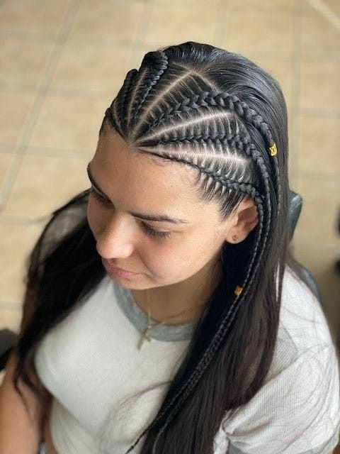 Mujer con cabello largo y oscuro, recogido en intrincadas trenzas africanas, vista desde arriba sobre un suelo de baldosas.