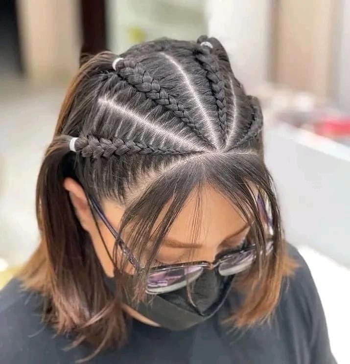 Peinado de trenzas africanas con raya al medio y trenzas laterales, visto desde arriba, en una clienta de salón