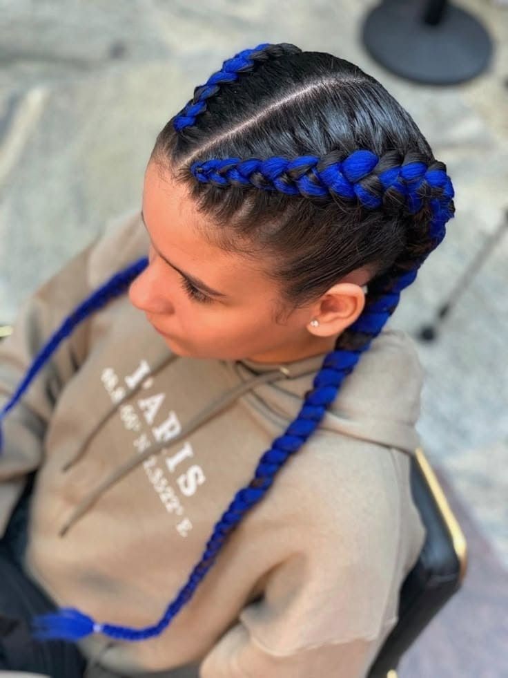 Persona con cabello azul trenzado que lleva una sudadera con capucha beige, vista desde arriba al aire libre.