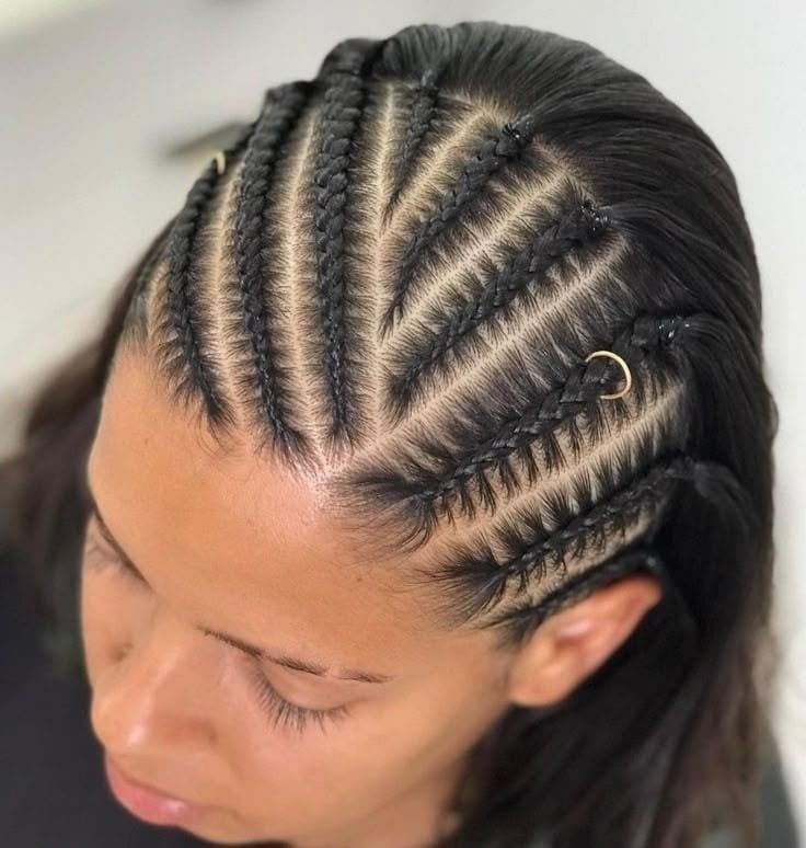 Primer plano de trenzas africanas elaboradas con esmero, con una pequeña pinza dorada para el cabello a un lado.
