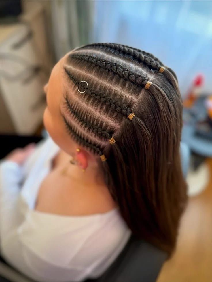 Trenzas africanas con cuentas doradas en la cabeza de una persona, vistas desde arriba en una silla de peluquería.