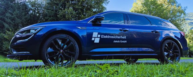Blaues Auto mit schwarzen Rädern auf einem gepflasterten Weg und grünem Gras.