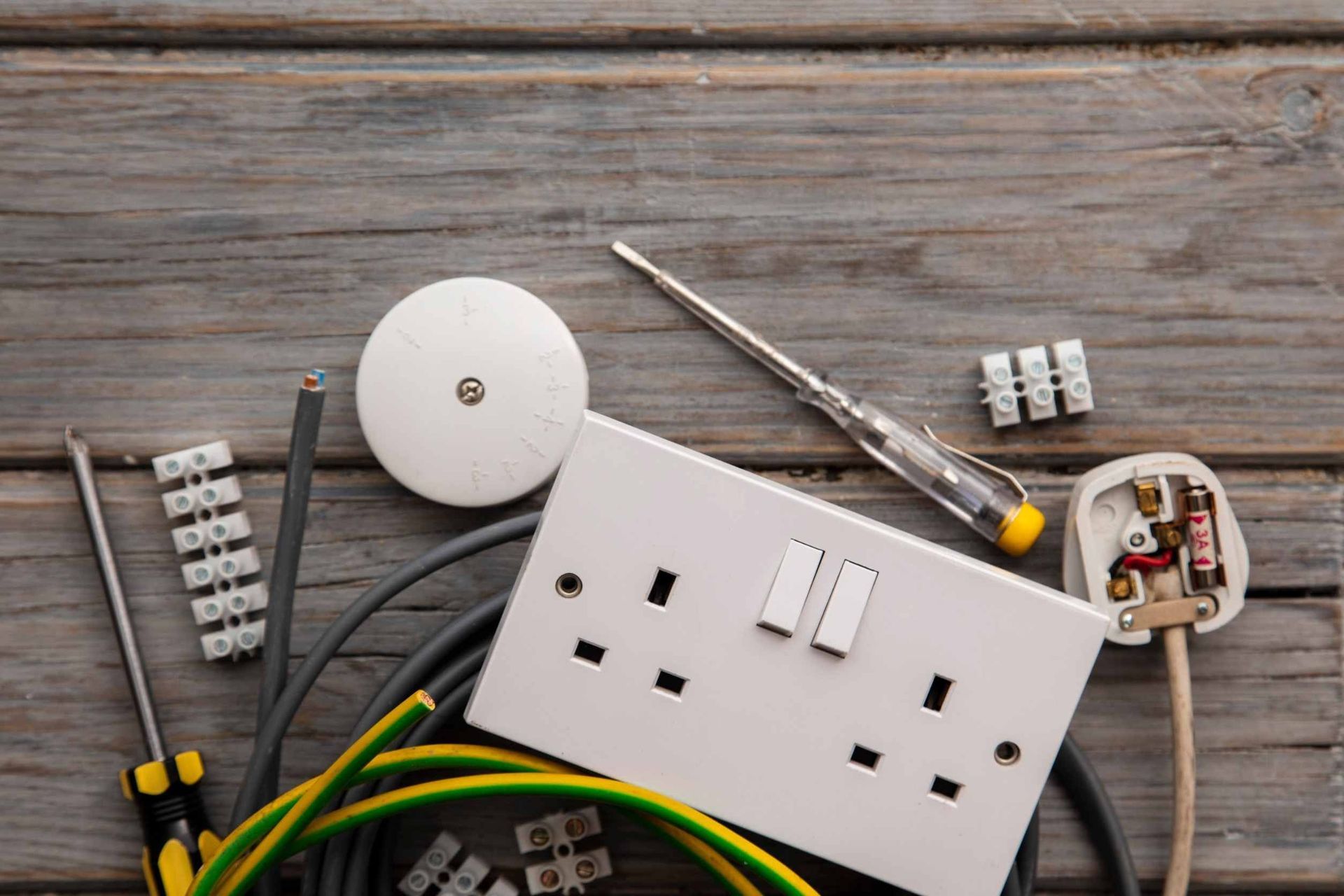 Una mesa de madera cubierta con equipos eléctricos y un enchufe.