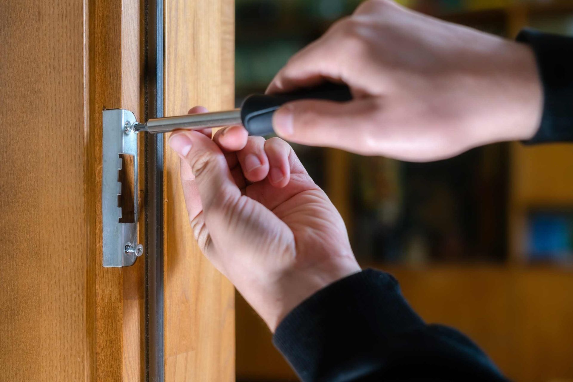 Una persona está arreglando una puerta con un destornillador.