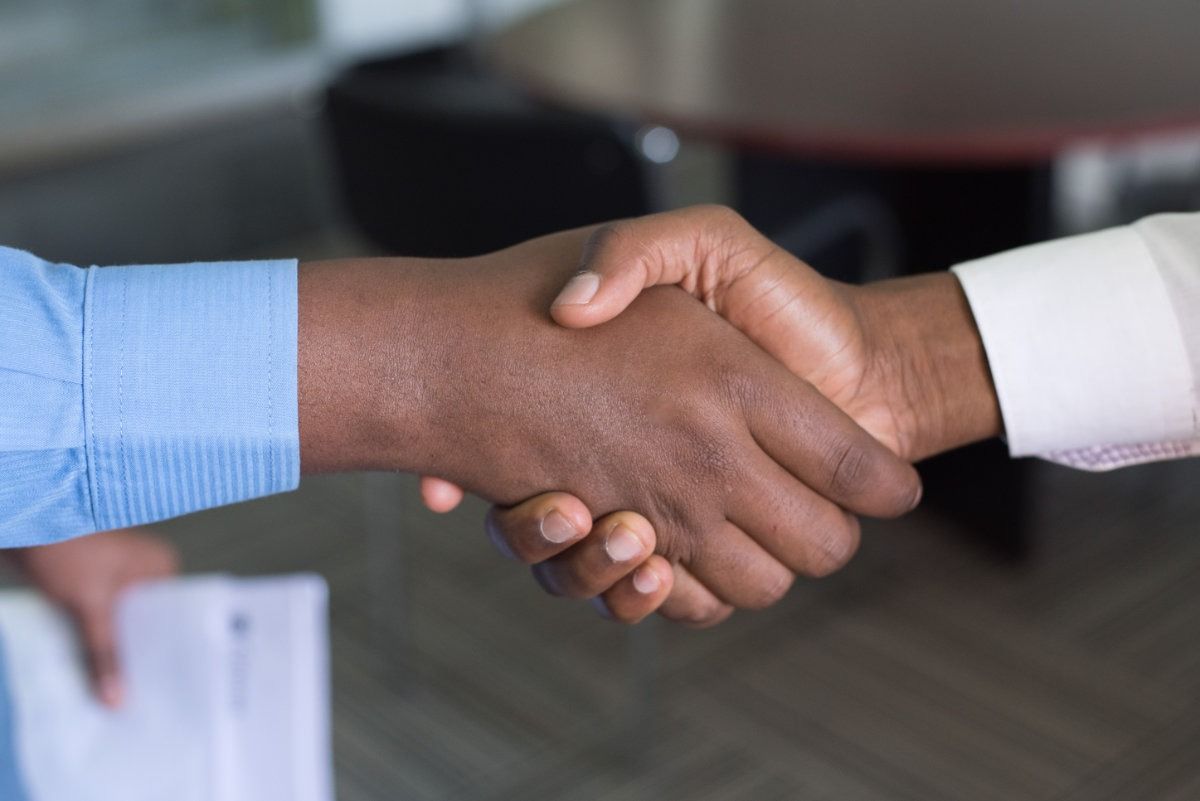 Un primer plano de dos personas dándose la mano en una oficina.