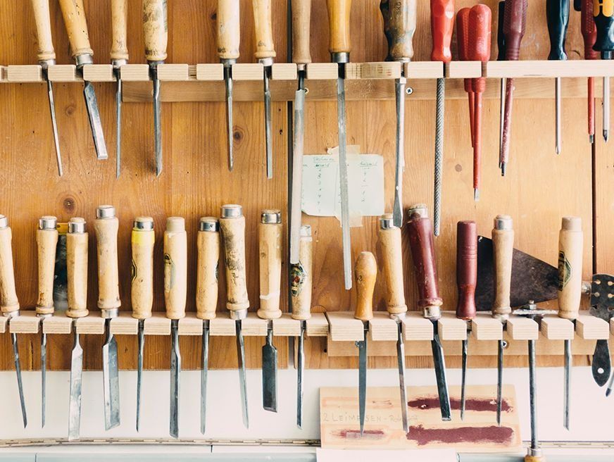 Un montón de herramientas para trabajar la madera están colgadas en una pared de madera.