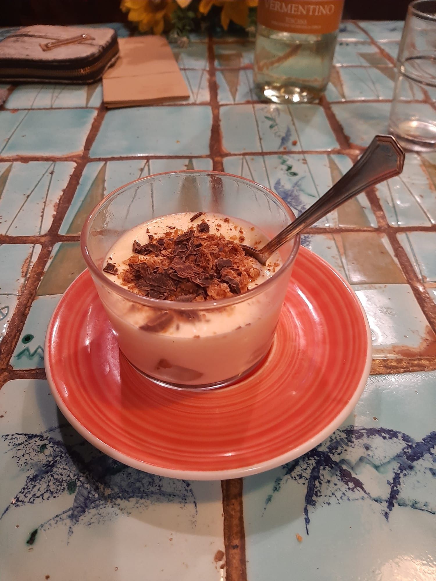 Un tazón de comida en un plato con una cuchara sobre una mesa.