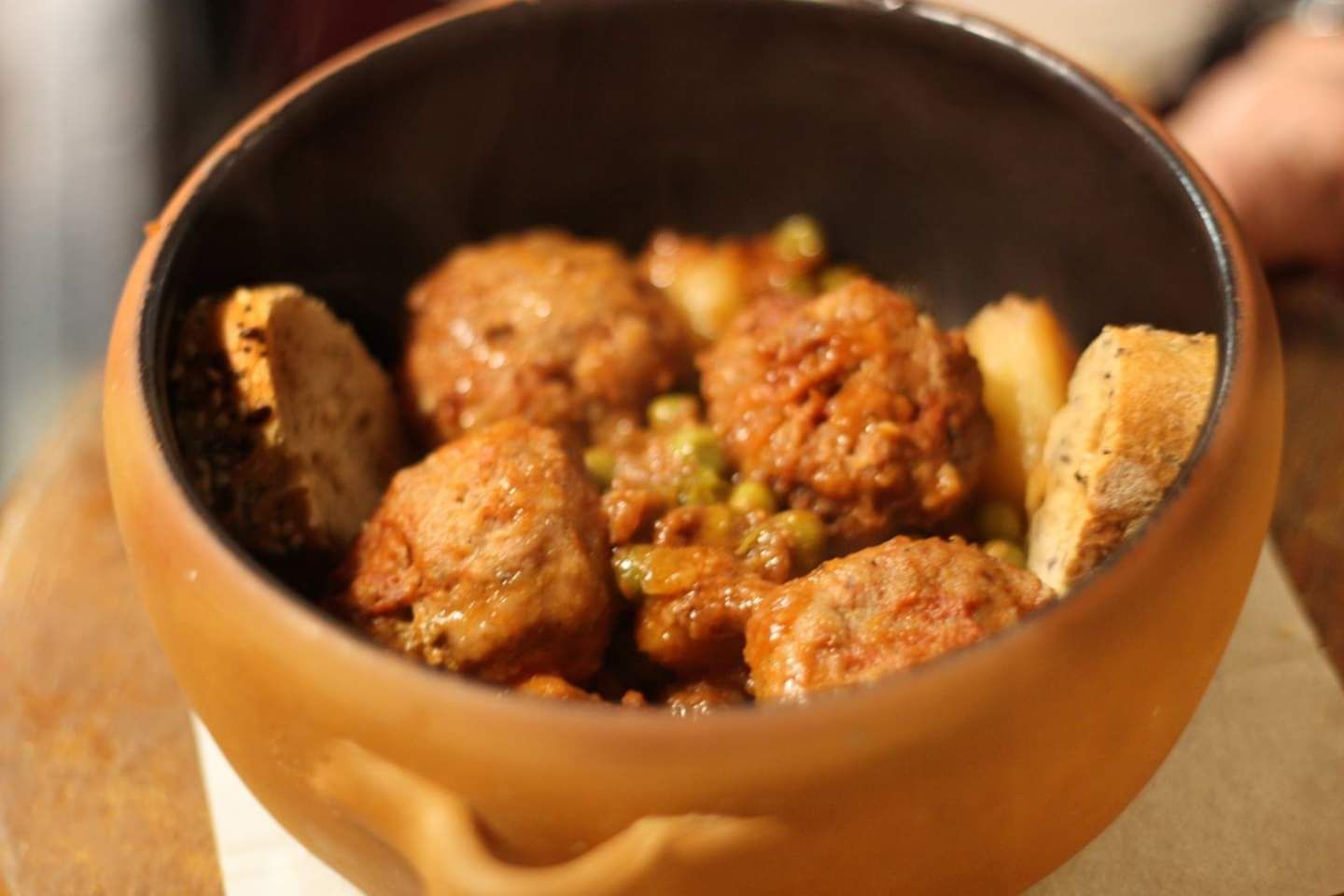 Un bol de albóndigas y pan sobre una mesa.