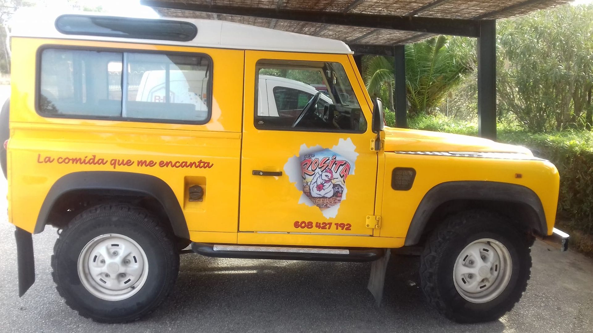 Un Land Rover amarillo está estacionado bajo un dosel.