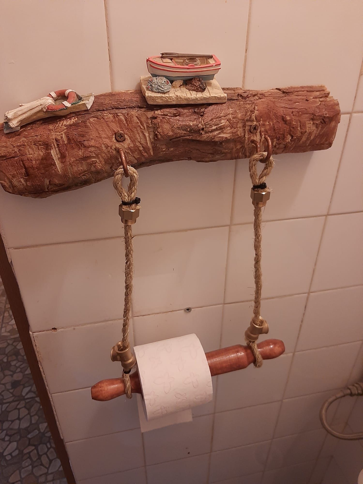 Un rollo de papel higiénico cuelga de un soporte de madera en un baño.