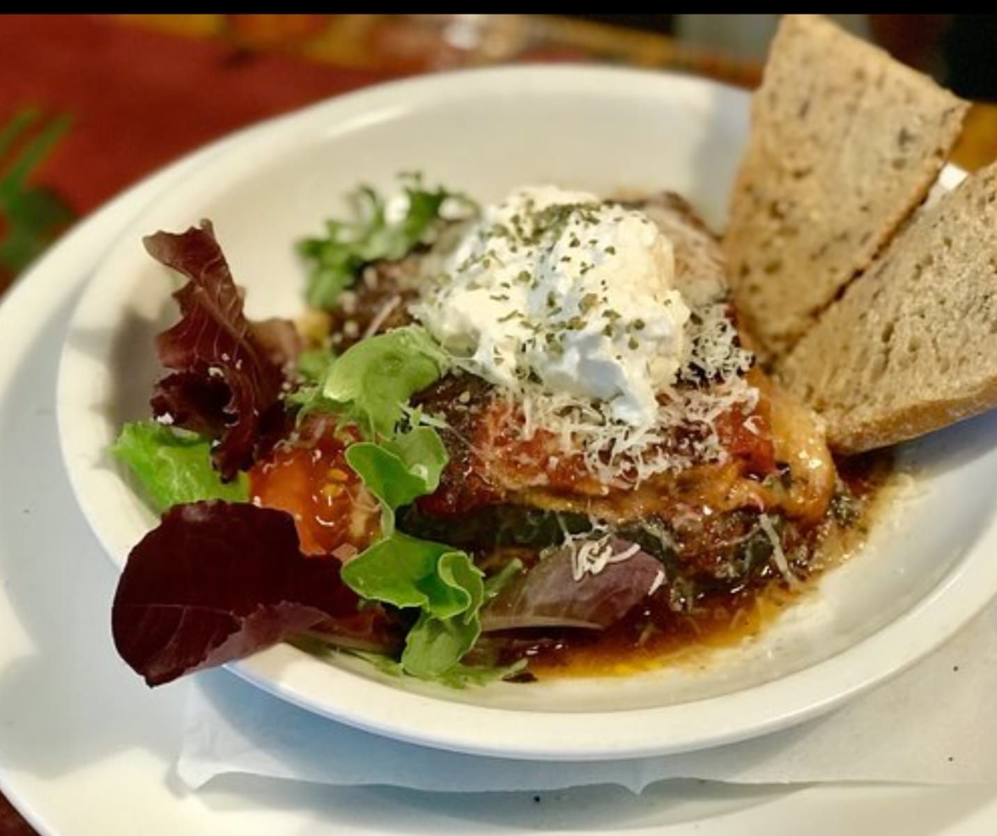 Un plato blanco cubierto con una ensalada y un trozo de pan.