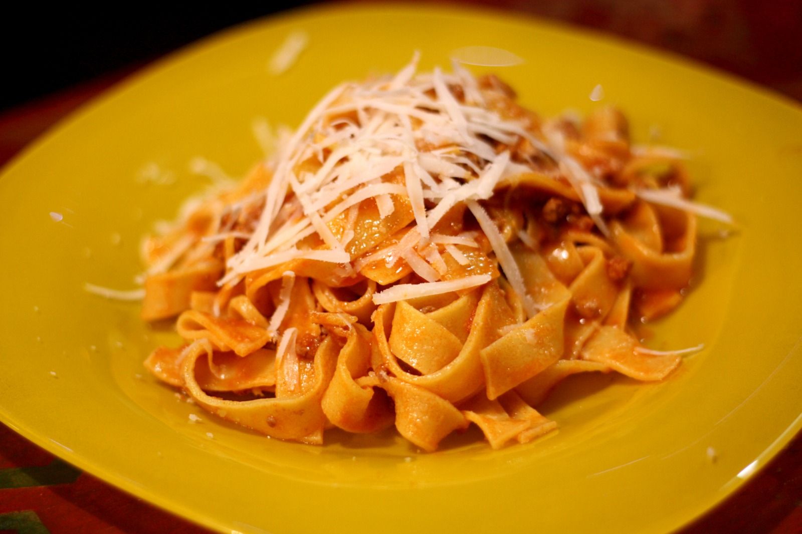 Un plato amarillo cubierto de pasta y queso sobre una mesa.