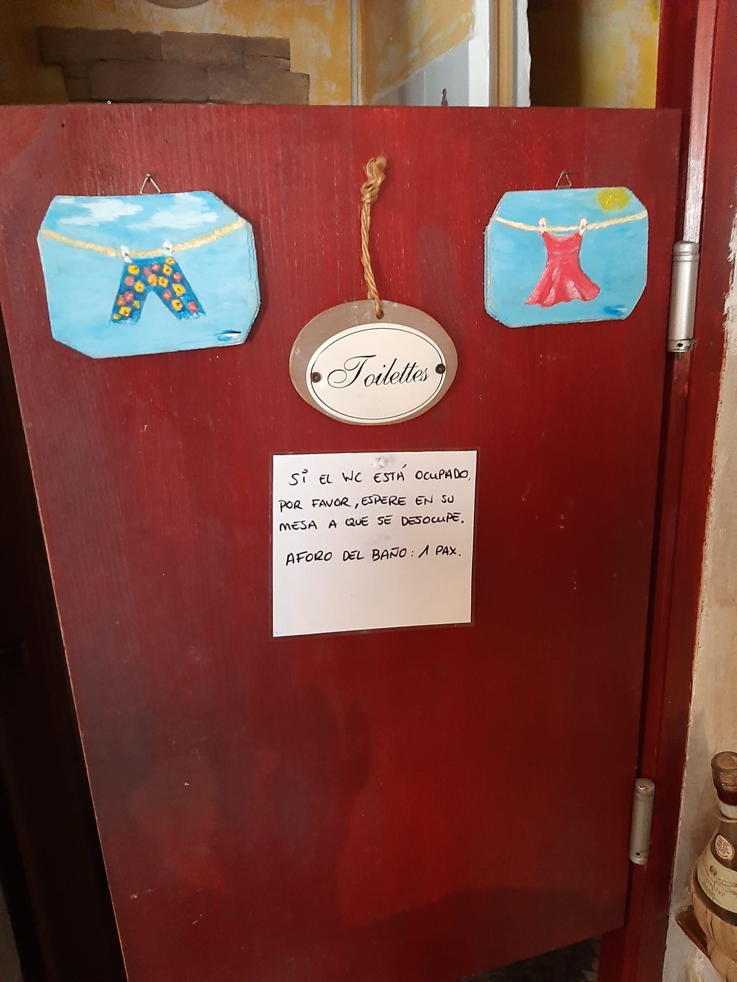 Una puerta roja con un cartel que dice baño.